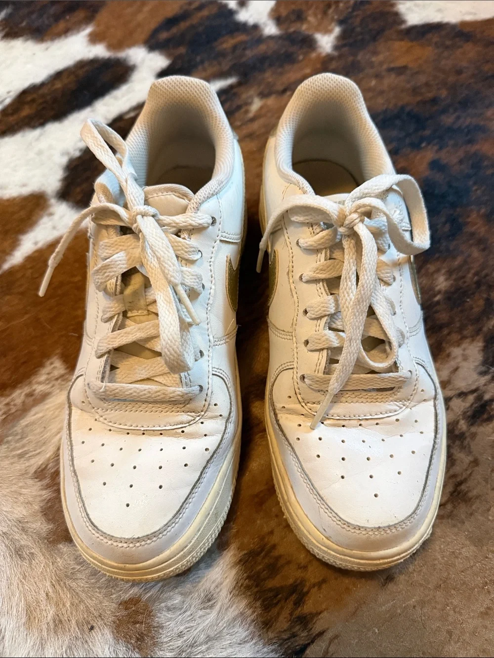 Nike low top Air Force ones. All white with gold swoosh.